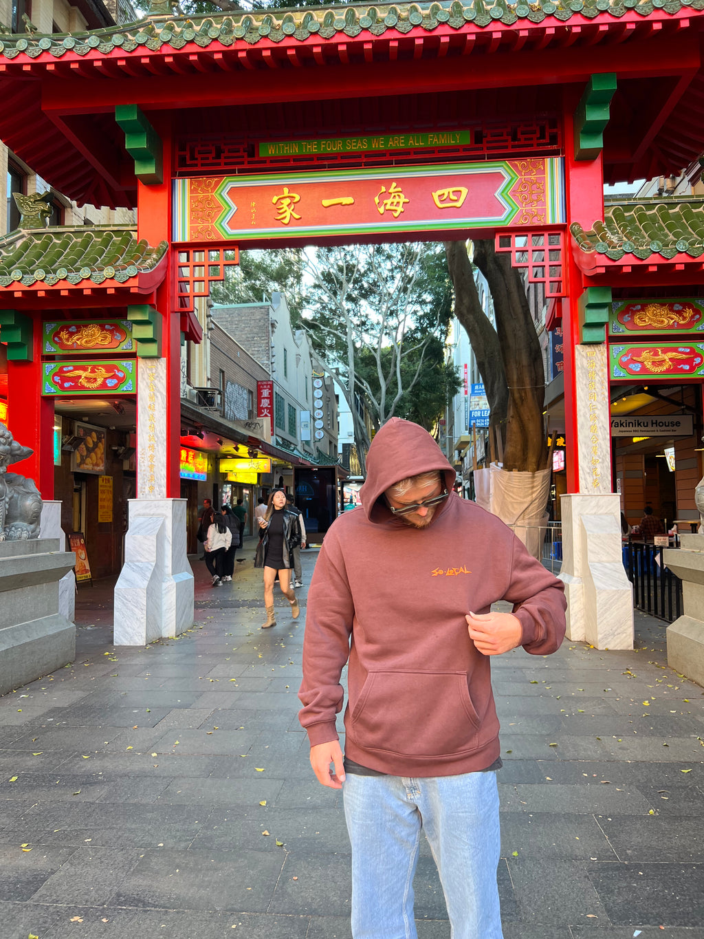 "I SEE YOU" SO LOCAL brown hoodie front logo, worn at the Sydney Chinatown gate