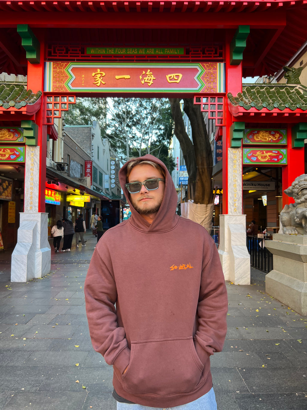 "I SEE YOU" SO LOCAL brown hoodie front logo, worn at the Sydney Chinatown gate